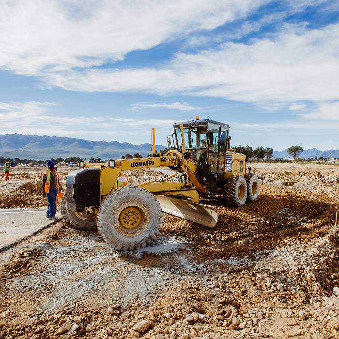 Motor grader shaping a road layer on a civil earthworks site