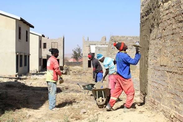 Builders plastering exterior walls on a housing project